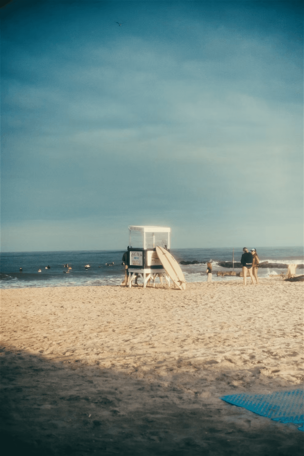 An Ocean City lifeguard stand and surfboard in warm beach light.