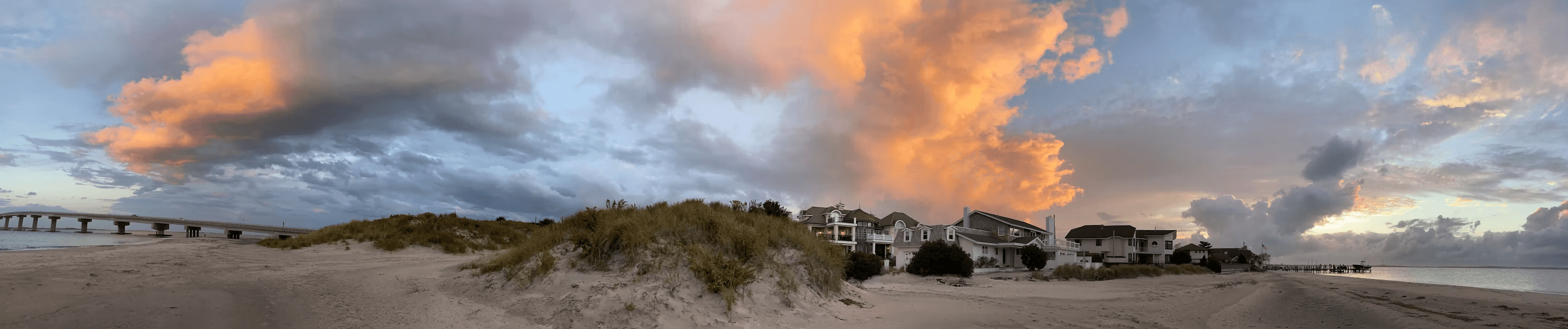 South end Ocean City dunes, bay bridge, Shore homes, and late-day clouds.